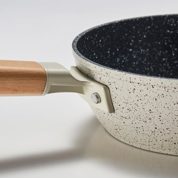 Close-up van een hoogwaardige koekenpan met antiaanbaklaag en houten handvat, die de duurzame, gespikkelde coating en het stevige ontwerp laat zien.