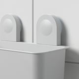 Twee witte RÅNEN opbergmanden voor de badkamer hangen aan de muur met zuignappen en bevatten shampooflessen.