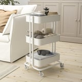 Witte RÅSKOG opbergwagen met planken, wielen, naast het bed.