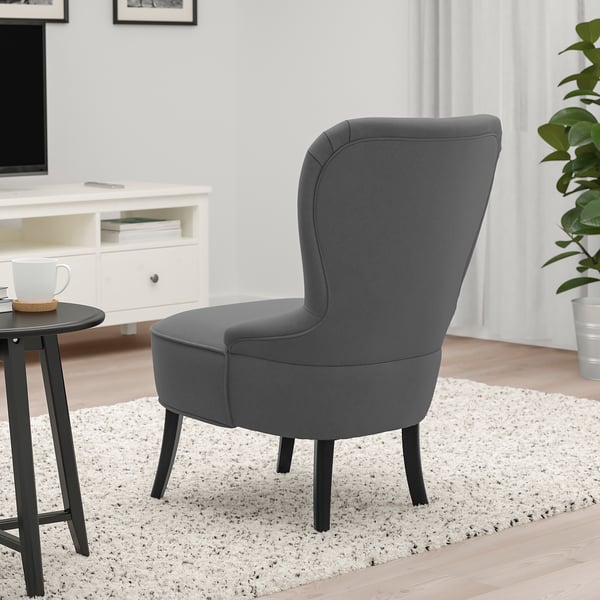 Moderne grijze fauteuil met hoge rugleuning voor lendensteun op houten poten, geplaatst op een getextureerd vloerkleed in een gezellige woonkamer.
