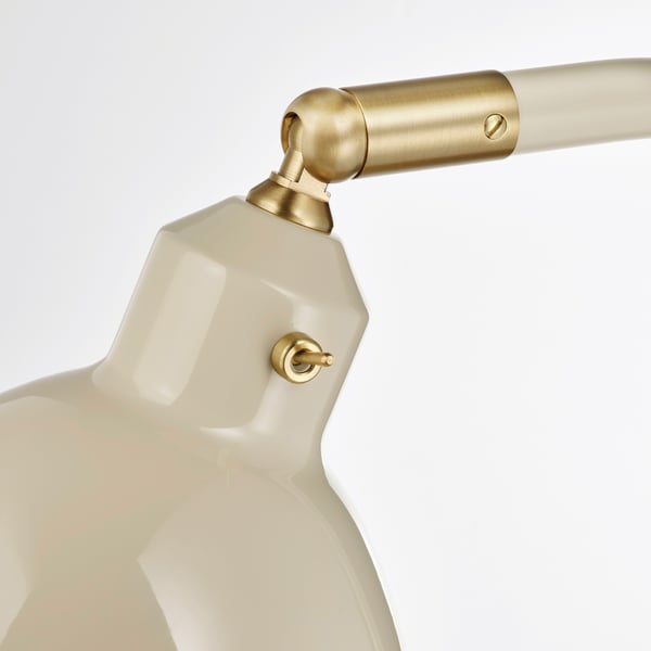 Close-up van moderne lamp, glanzende witte kap, gouden accenten, verstelbare gewrichten.