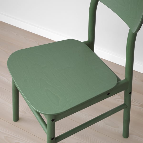 Moderne groene stoel met gladde, afgeronde hoeken en zichtbare houtnerf, die robuust vakmanschap laat zien.