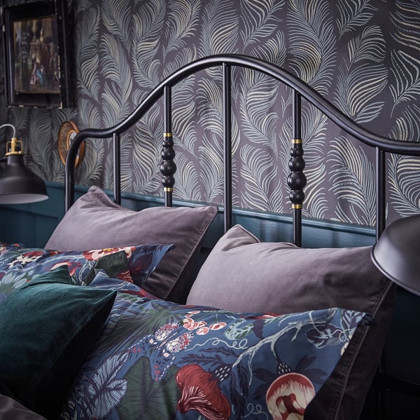 Elegant zwart metalen bed, SAGSTUA, met messing details. Stevig stalen frame, gebogen hoofdeinde en sierkussens.