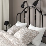Een stijlvol zwart metalen bedframe met messing accenten, voorzien van een gebogen hoofdeinde en verstelbare leeslampjes aan de muur.