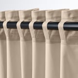 Gordijnen hingen met lipjes aan de stang, filterden licht en voegden warmte toe. Neutraal beige met fluwelen textuur, waardoor privacy wordt gecreëerd.