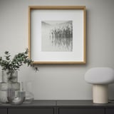 Een minimalistische wanddisplay met een ingelijste zwart-wit natuurfoto, omringd door decoratieve vazen en een moderne lamp.