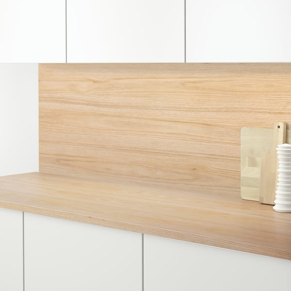 Houten aanrecht met lichte houten paneelachterwand, met een snijplank en een kleine vaas.