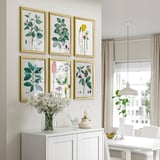 Moderne woonkamer met botanische prints, witte kast, vaas met bloemen en eethoek.