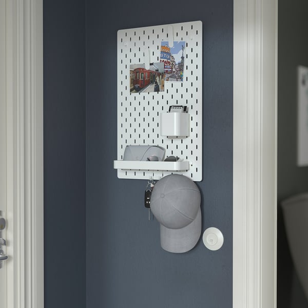 Op het SKÅDIS ophangbord aan de muur staan spullen zoals sleutels, portemonnee en hoed. Het bevat een bekerhouder en een opbergplank.