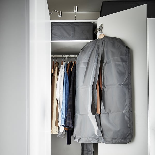 Afgesloten kast met kledinghangers, waaronder een grijze kledingzak en diverse overhemden.