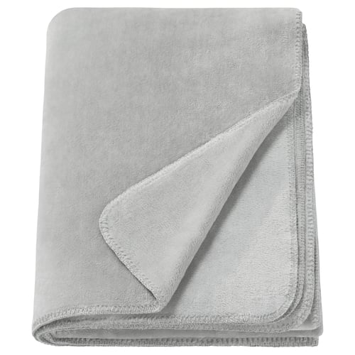 Een opgevouwen lichtgrijze SLÅNGRÅMAL deken gemaakt van zacht, gerecycled polyester. Het heeft een glad, uniform ontwerp met gestikte randen.