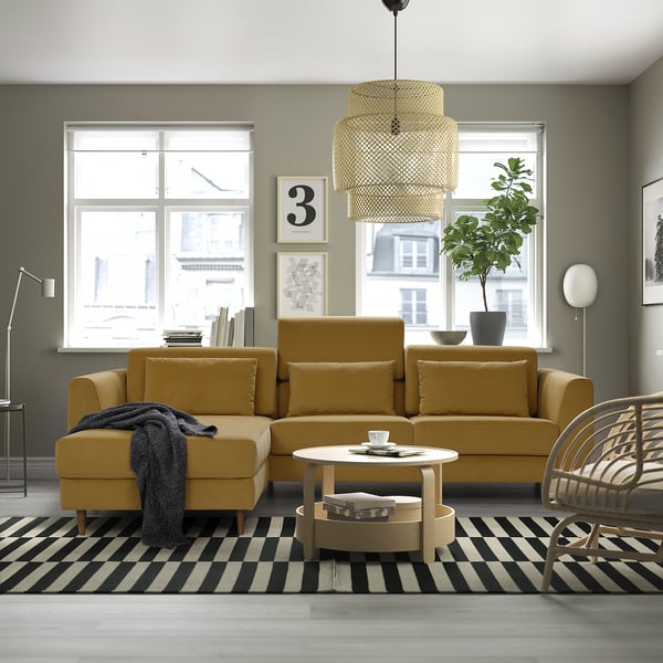 Moderne woonkamer met gele sectionele bank, gestreept vloerkleed en grote ramen.