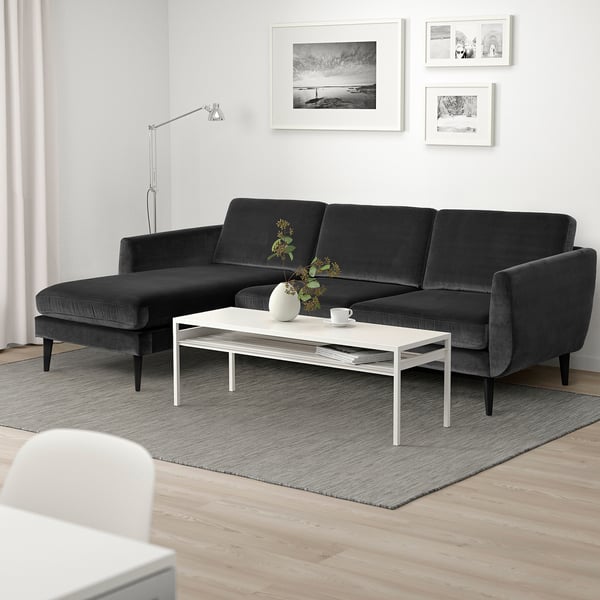 Moderne grijze sectionele bank met chaise longue, witte salontafel, zwart-witte kunst, grijs tapijt, houten vloer.