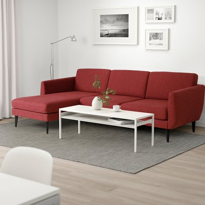Rode retro-stijl bank met zachte vormen & kegelpoten in minimalistische woonkamer.