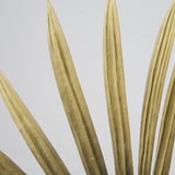 Luxe gouden kunstgrasbladen, realistisch en met precisie vervaardigd, weergegeven tegen een lichte achtergrond.