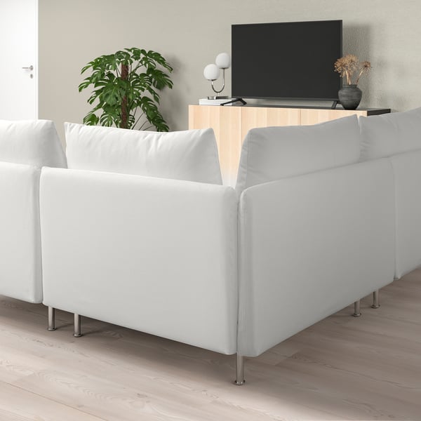 Moderne witte sectionele bank in minimalistische woonkamer met tv en plant.