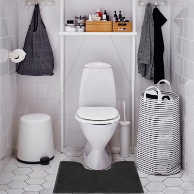 Badkamer met toilet, donkergrijze mat, witte prullenbak, gestreepte mand.