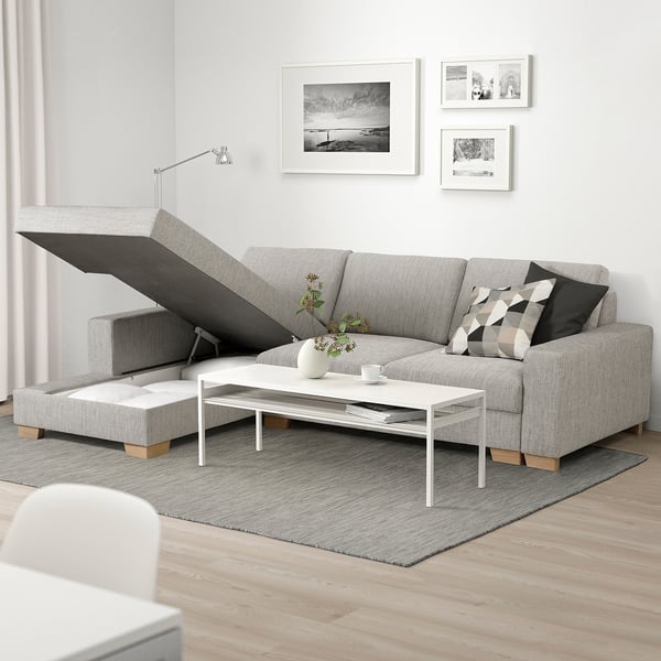 Moderne woonkamer met l-vormige SÖRVALLEN-bank, voorzien van chaise longue en opbergruimte. Versierd met kussens, vaas en salontafel op een kleed.