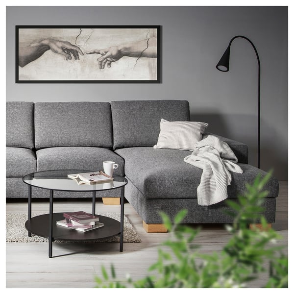 Moderne woonkamer met grijze SÖRVALLEN-bank, zwarte salontafel en michelangelos de creatie van adamkunst erboven.