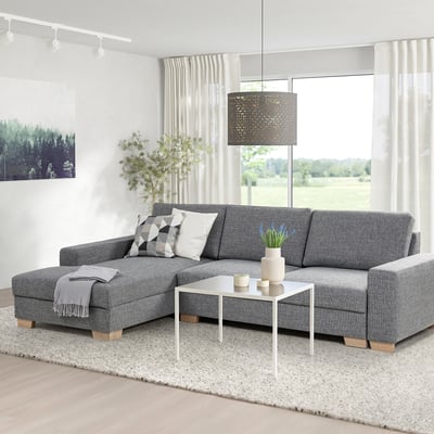 Grijze u-vormige bank met chalay, kussens, plaid, vaas met blauwe bloemen, salontafel, vloerkleed, grote ramen, hanglamp.