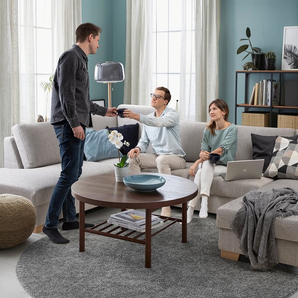 Drie in de moderne woonkamer, een met afstandsbediening, twee op de bank, ontspannen, minimalistische inrichting.