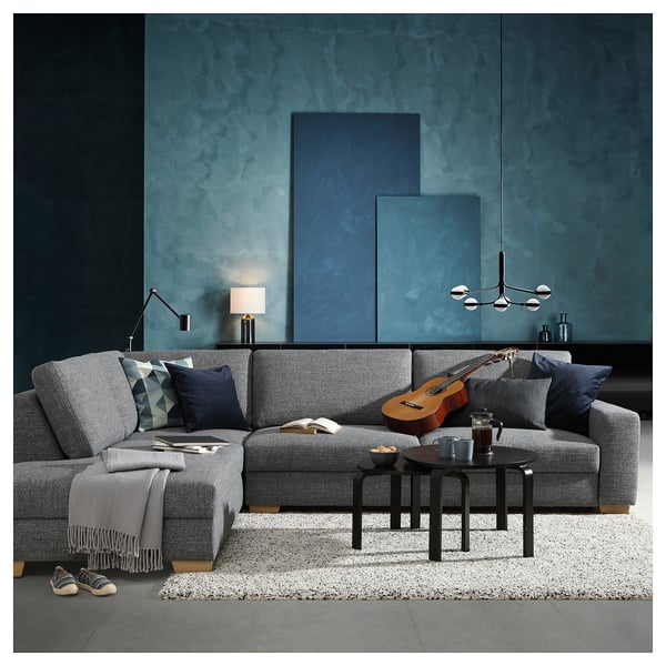 Moderne woonkamer met grijze SÖRVALLEN bank, donkerblauwe kunst aan de muur, zwarte salontafel en gitaar.