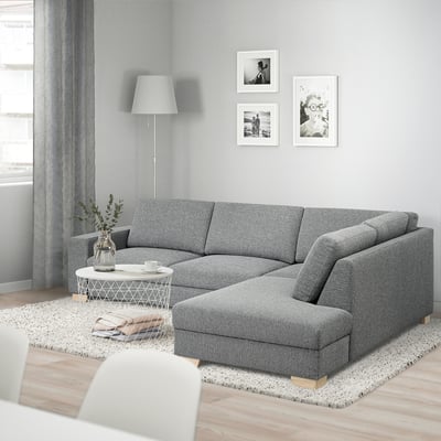 Moderne grijze l-vormige SÖRVALLEN-bank in minimalistisch design, groot in vergelijking met bijzettafel, met kunst aan de muur erboven.