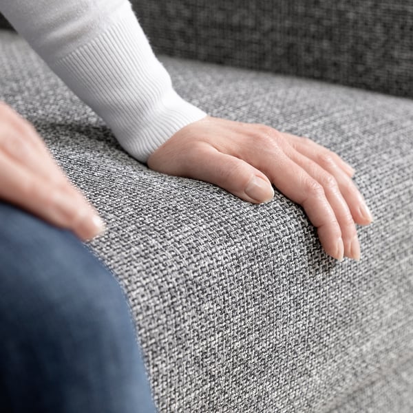 Persoon die hand op grijze bank rust, die witte koker draagt.