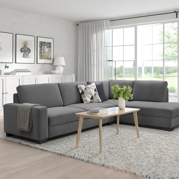 Moderne Scandinavische woonkamer met grijze SÖRVALLEN sectionele bank, kussens, houten salontafel en groot raam.