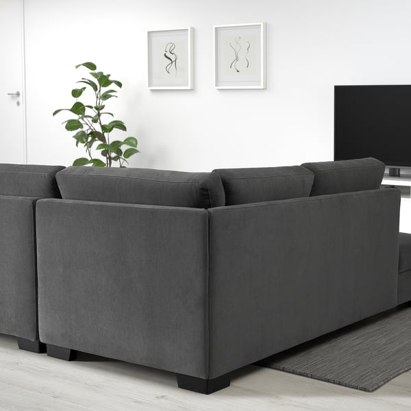 Grijze bank SÖRVALLEN: modern, rechthoekig, met zachte kussens. Het is groot, past goed in ruime kamers, met kunst en een plant in de buurt.