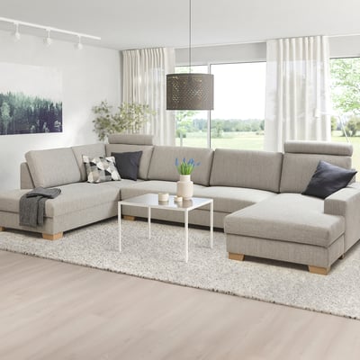 Moderne l-vormige bank met neutrale kleuren, minimalistisch design, houten poten, bij het raam, met vloerkleed en kussens.