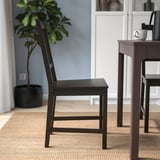 Een stevige houten stoel met een hoge rugleuning, ideaal voor dagelijks gebruik, geplaatst bij een tafel.