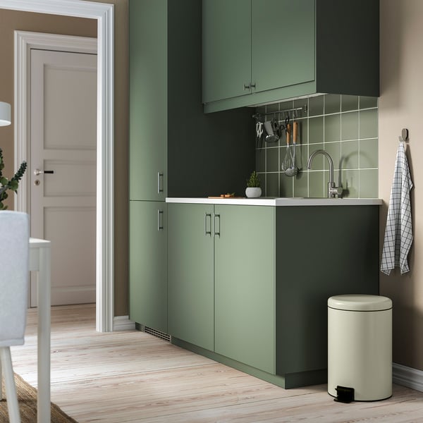 Moderne groene keuken met STJÄRNHOV chromen handgrepen, roestvrijstalen gootsteen en een kleine witte vuilnisbak.