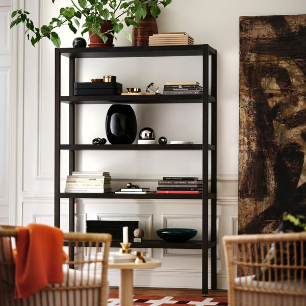 Moderne zwarte metalen rekken tonen boeken, vazen en decor; Groter dan houten stoelen.
