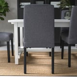 Drie moderne eetkamerstoelen met grijze stoffen bekleding en zwarte metalen poten rondom een witte uitschuifbare tafel op een getextureerd vloerkleed.