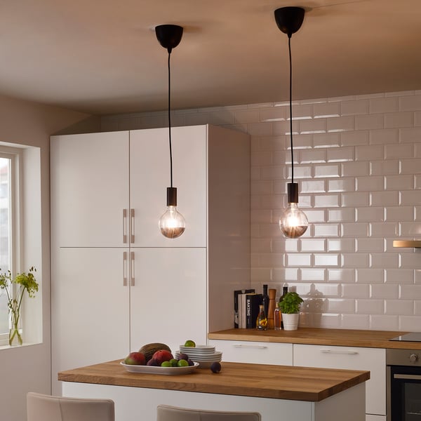 Twee SUNNEBY hanglampen boven kookeiland met fruit, borden en plant.