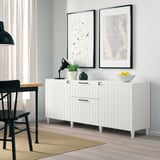 Moderne woonkamer met wit dressoir, art prints en zwart bureau.