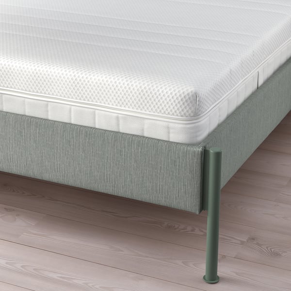 Modern bedframe met grijsgroen gestreept patroon, gewatteerd hoofdeinde en metalen poten die ondersteuning en opbergruimte bieden.