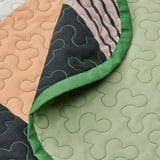 Close-up van de TALLSVÄRMARE patchwork sprei in groen, met de nadruk op zachte, gerecyclede stof met ingewikkelde patronen.