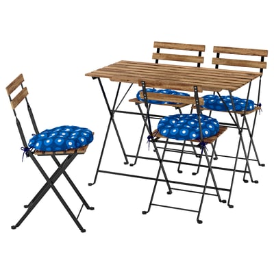 Houten buitentafel en vier inklapbare stoelen met blauwe stippenkussens.
