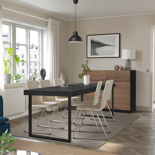 Moderne eetkamer met zwarte uitschuifbare tafel, beukenhouten stoelen en houten kast.