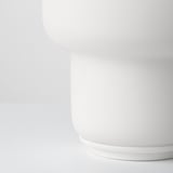 Strakke, moderne lamp met gladde, afgeronde glazen kap bovenop een strakke polyvoet. Minimalistisch ontwerp.