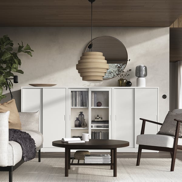 Moderne woonkamer met TONSTAD gebroken witte kast, ronde houten tafel, stoelen en stijlvolle verlichting.