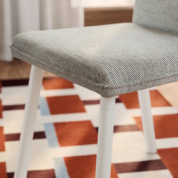 Moderne eetkamerstoel met strakke witte poten, grijze tweed zitting en pluche vulling, die hoogwaardig comfort en stijl uitstraalt.