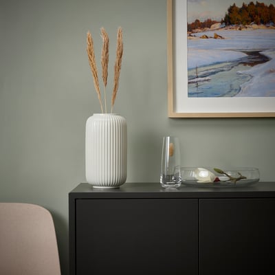 Moderne woonkamer met TORKA vaas, droogbloemen, decoratieve artikelen en gedeeltelijk uitzicht op de stoel.