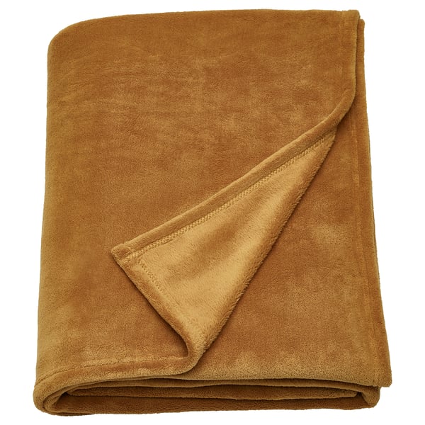TRATTVIVA mosterdgele fleece sprei, zacht en warm, netjes opgevouwen.