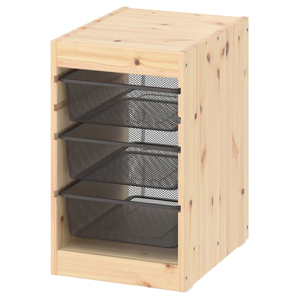 Een TROFAST opbergmeubel in licht grenen met drie zwarte gaaslades, ideaal voor het organiseren van spullen.