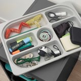 Georganiseerde opbergbak met meerdere compartimenten voor kleine spullen zoals pennen, sleutels en accessoires.