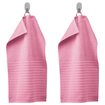 Twee roze VÅGSJÖN-handdoeken hangen naast elkaar aan metalen haken, met een zacht gestructureerd ontwerp en levendige kleuren.