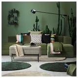 Moderne woonkamer met groene VALTORP bank, kleurrijke kussens, cactus decoraties en een gezellig vloerkleed.